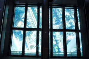 Looking down through the glass floor to the streets far below.